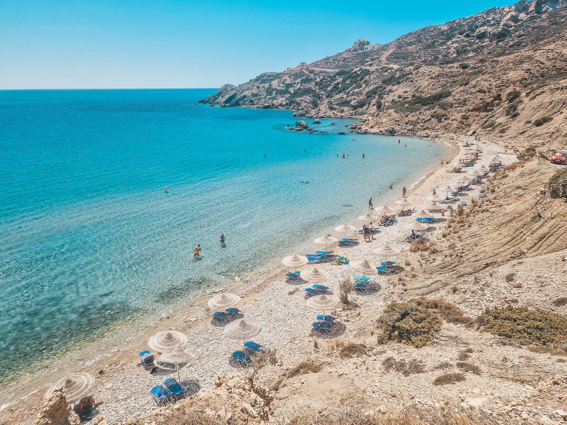 Strandbedjes met parasols op een strand op Karpathos
